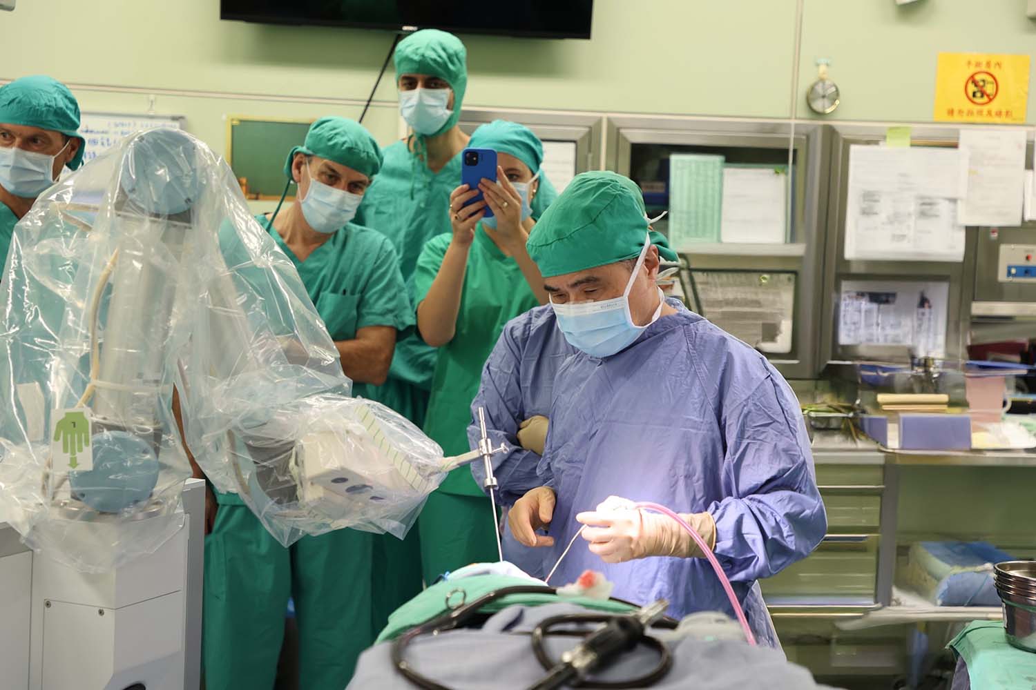 醫生在手術室進行腦部手術,周圍有其他醫療人員觀察,手術儀器、設備在旁,醫生專注於手術過程中。